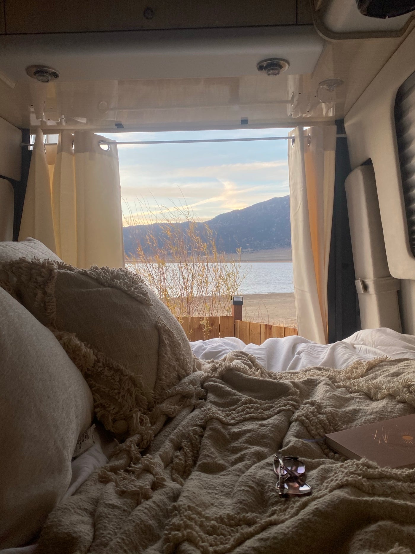 RV rental: Cozy bedroom with a stunning lake and mountain view from bed. Curtains frame nature's beauty. — photo 3