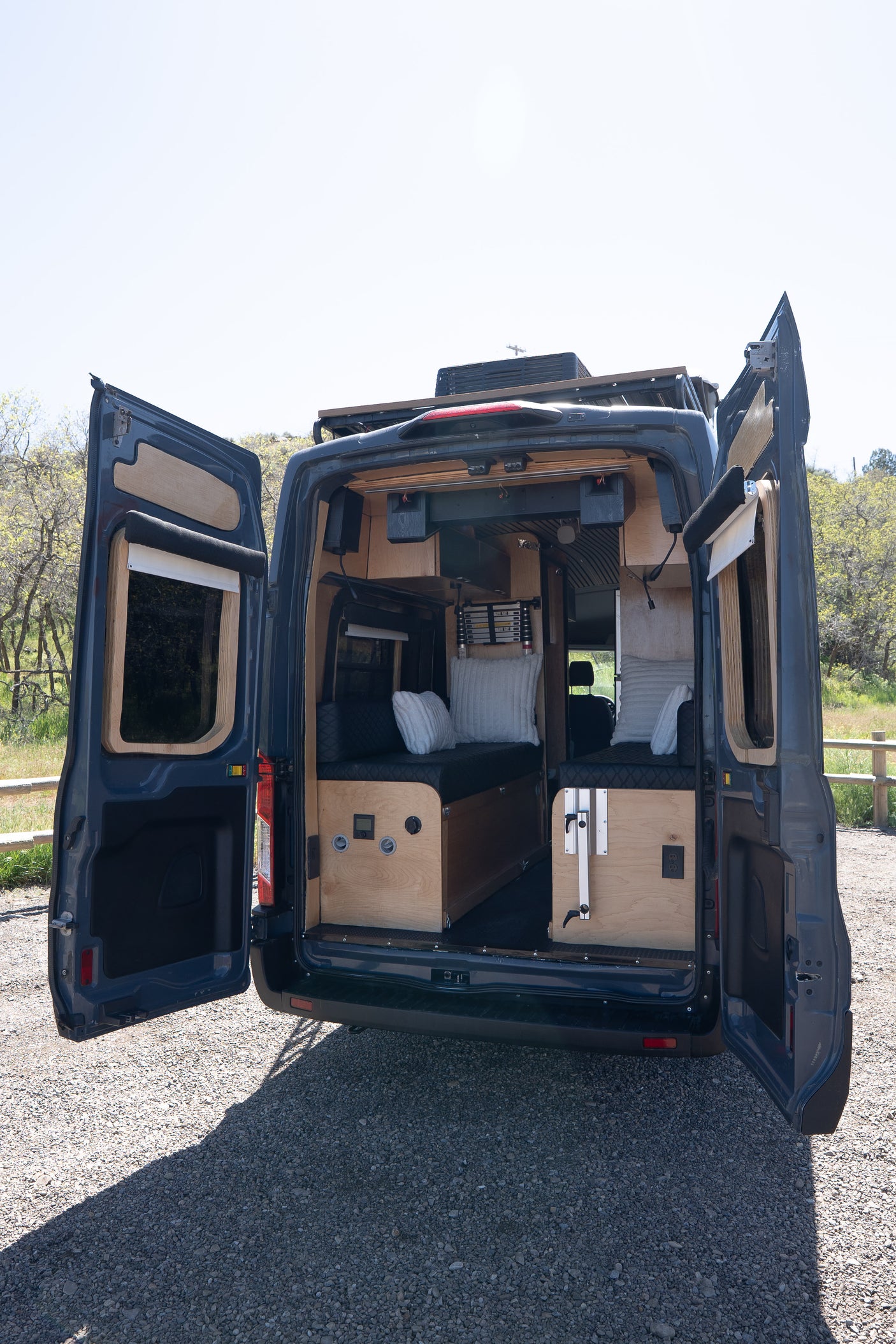 Explore the custom interior of this dark blue camper van, featuring cozy seating and wood paneling, ideal for an RV rental adventure.