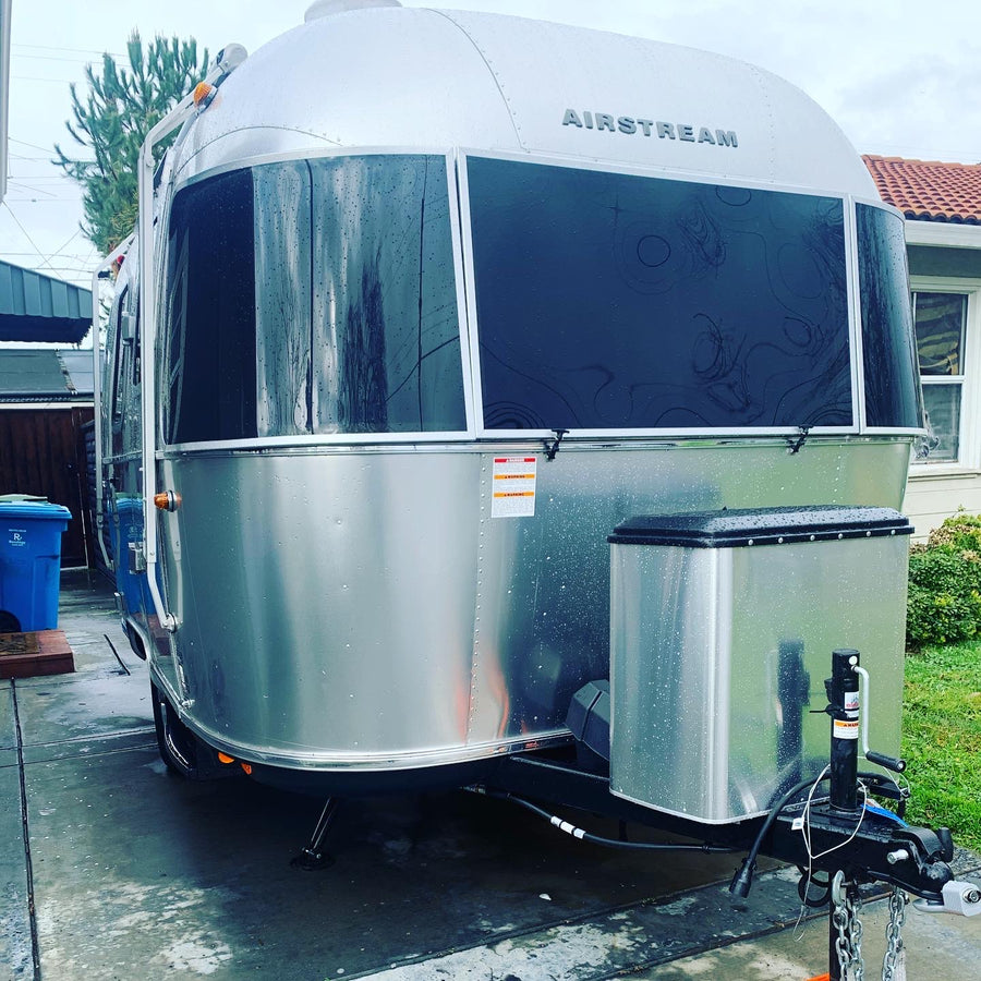 A shiny silver Airstream travel trailer, a potential RV rental, glistening wet. Perfect for your next outdoor adventure.