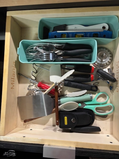 **RV rental** kitchen drawer with various utensils, a level, and a Stanley multi-tool, organized in bins.