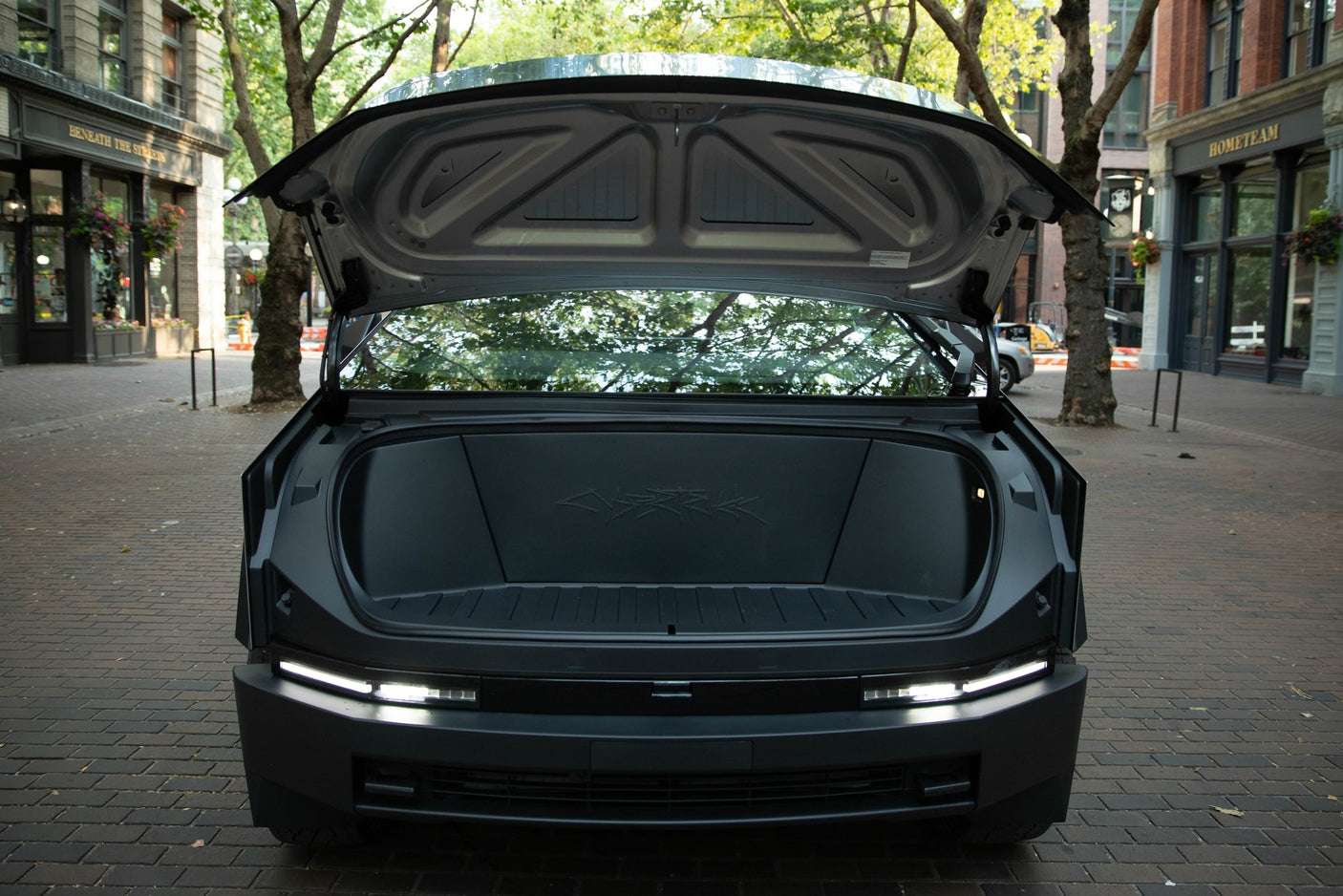 Rear view of dark, modern vehicle with trunk open, showing spacious cargo & bright LED lights. Great for your next RV rental trip.