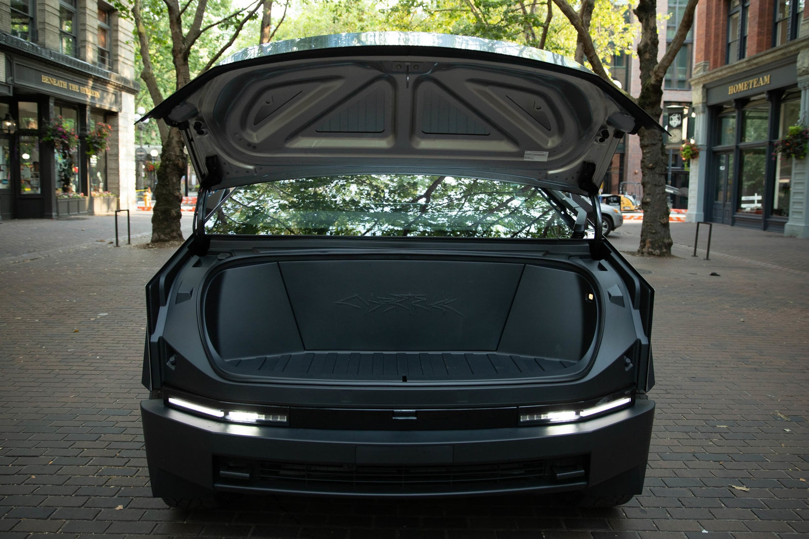 Rear view of dark, modern vehicle with trunk open, showing spacious cargo & bright LED lights. Great for your next RV rental trip.
