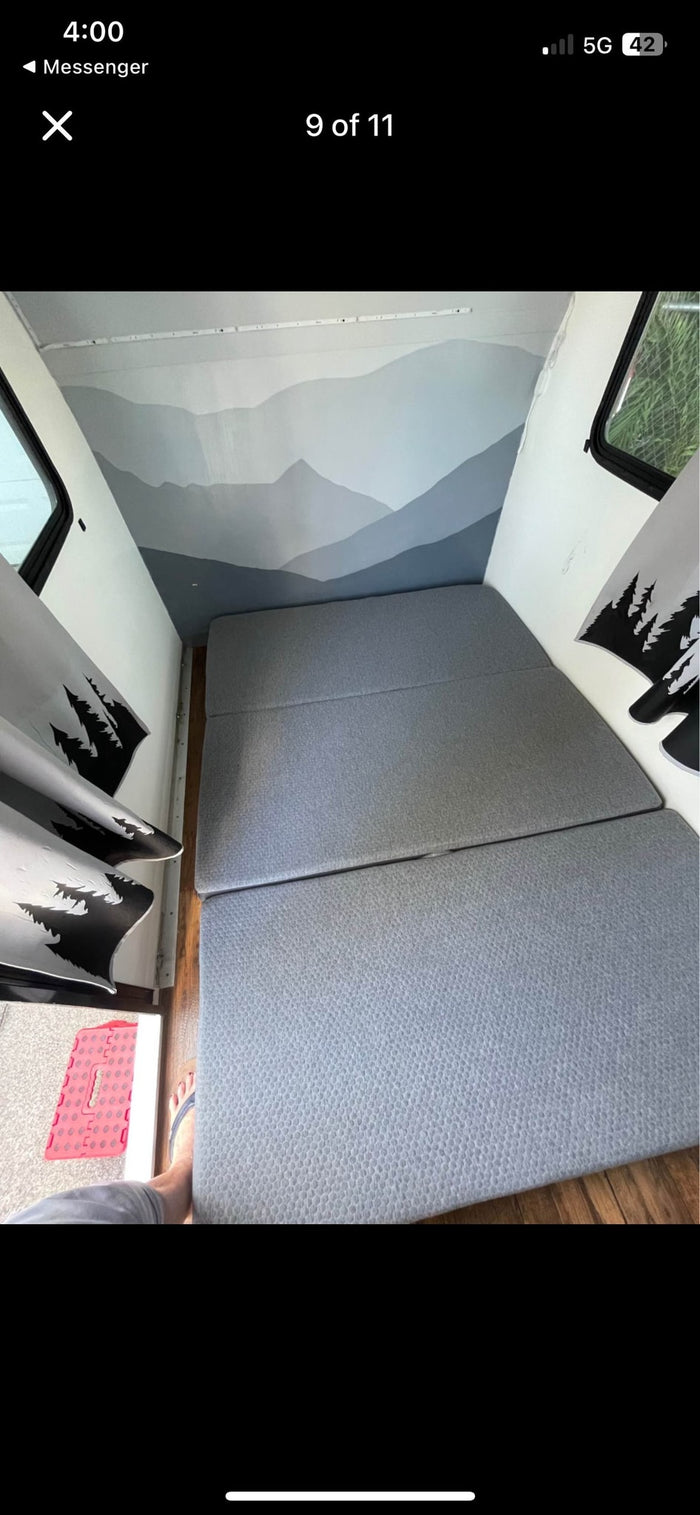 set against a light mountain mural wall and strip lighting.|Cozy RV rental interior with a foldable bed