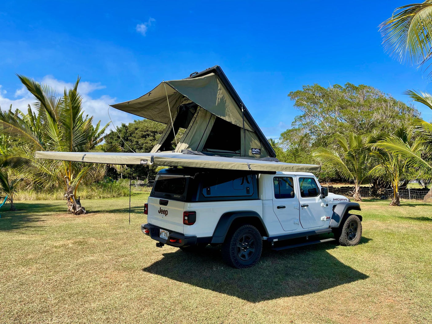 This white Jeep Gladiator with an Alpha Omega rooftop tent and awning offers an ideal RV rental experience for tropical overlanding.|Golden sunset on a beach
