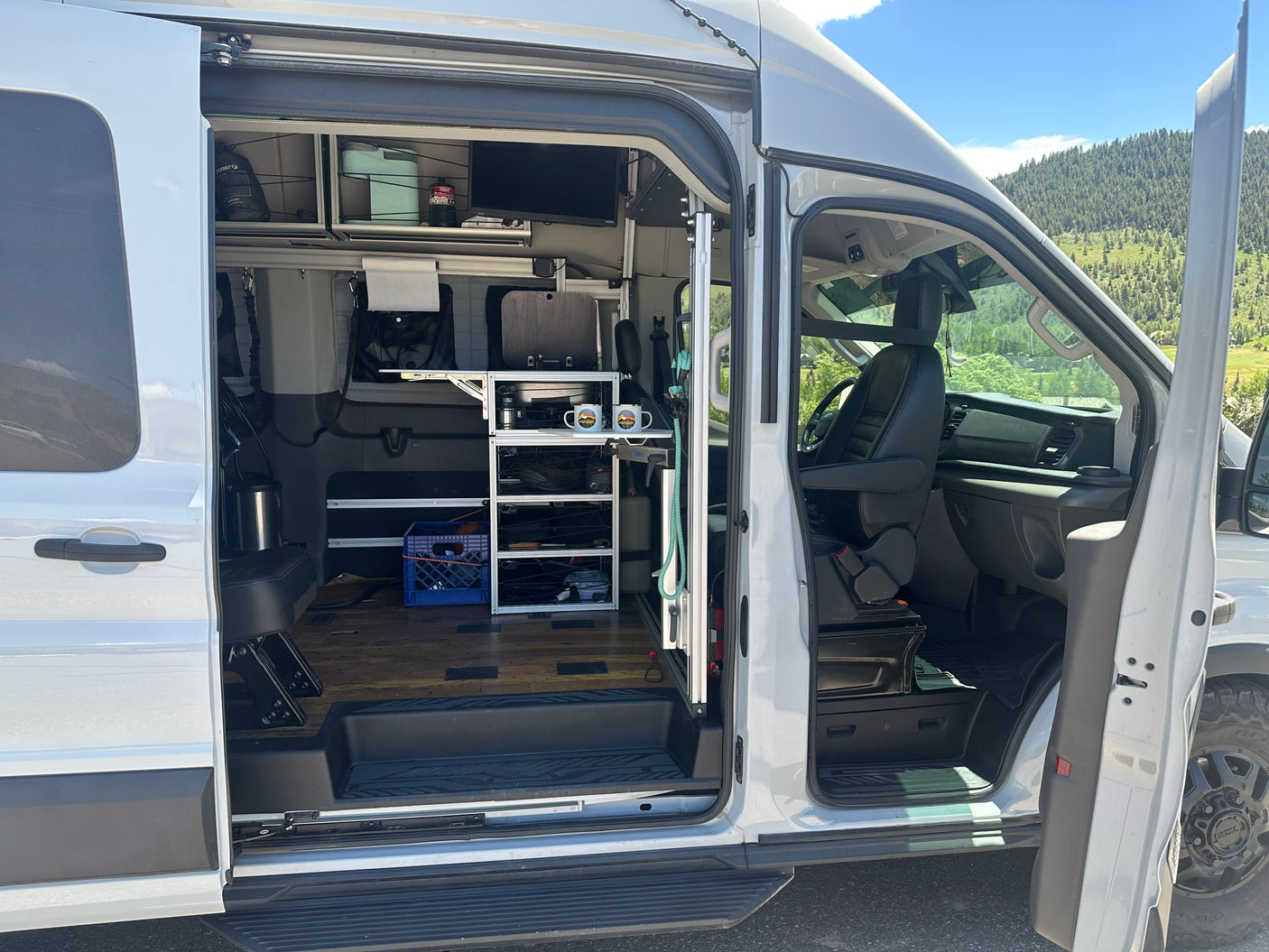 Spacious RV rental camper van interior with modular storage, TV, and outdoor view. Ready for van life adventures!