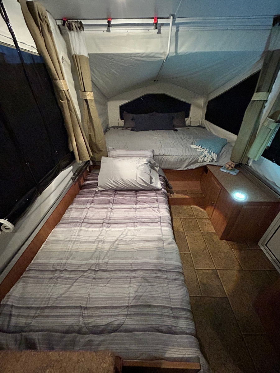 Inside a comfy rv rental, featuring two neatly made beds, curtains, and soft interior lighting for a relaxing night.