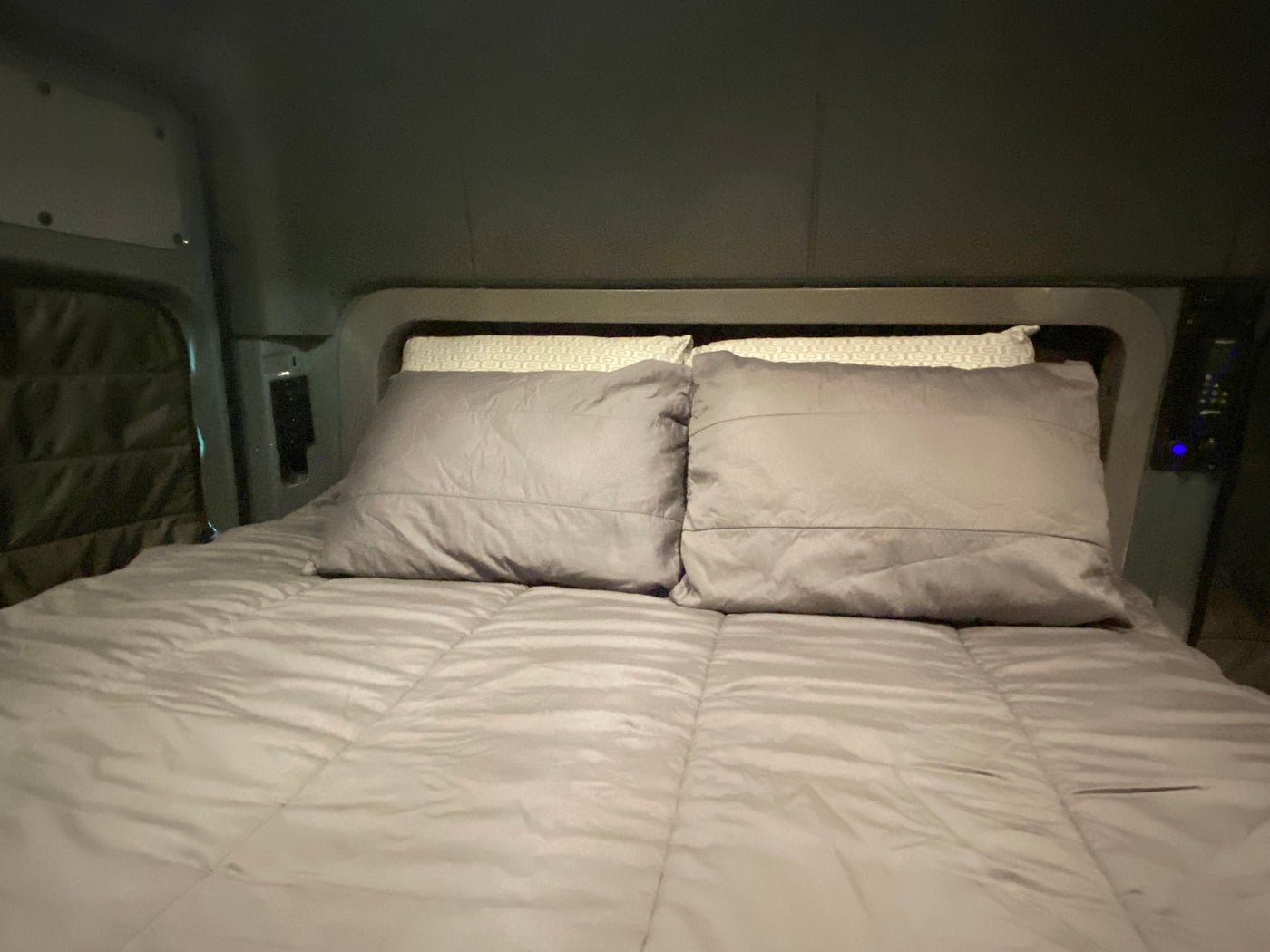 Comfortable grey bed and pillows inside an RV rental. A cozy, compact sleeper space for your travels. — photo 15