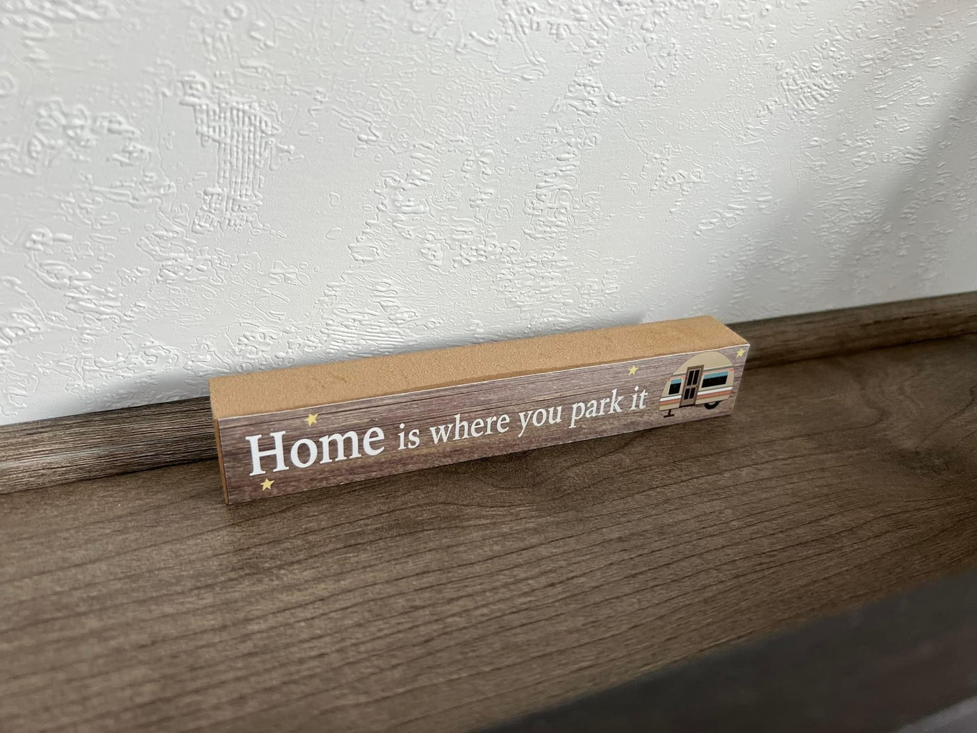 A wooden sign reading "Home is where you park it" with an RV graphic, inspiring your next RV rental adventure.