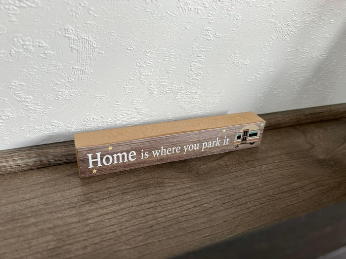 A wooden sign reading "Home is where you park it" with an RV graphic, inspiring your next RV rental adventure.