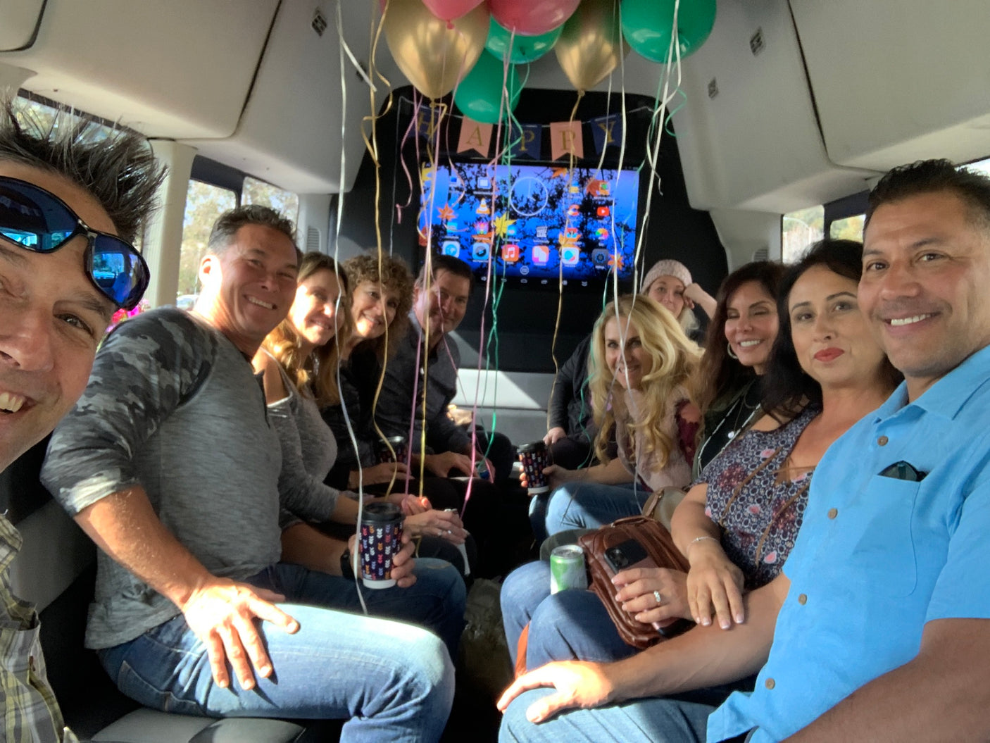 Friends celebrating in a spacious RV rental, complete with balloons and a TV for entertainment. Everyone's smiling!