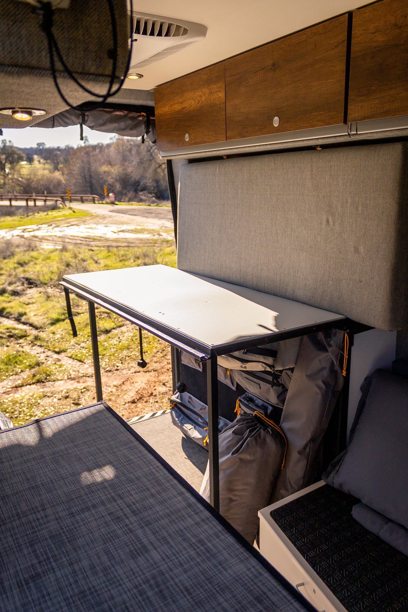 RV rental interior featuring a versatile table overlooking a scenic outdoor road and organized storage.