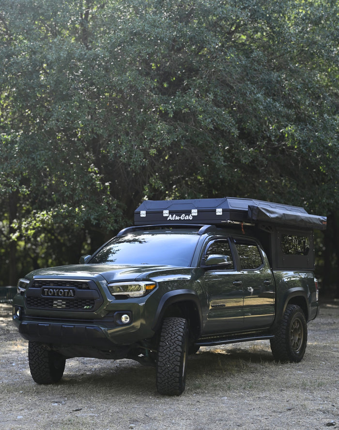 Dark green Toyota Tacoma pickup with Alu-Cab camper, perfect for an RV rental adventure.