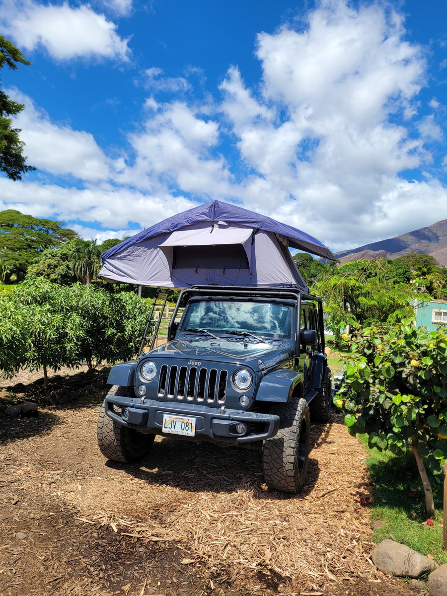 Rooftop tent on a Jeep, a unique RV rental for outdoor adventures under a blue, cloudy sky.