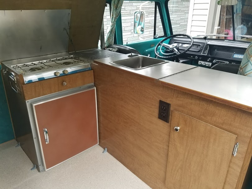 interior kitchen visible. Great for RV rental adventures.|Cozy RV rental interior with retro gold quilted seating