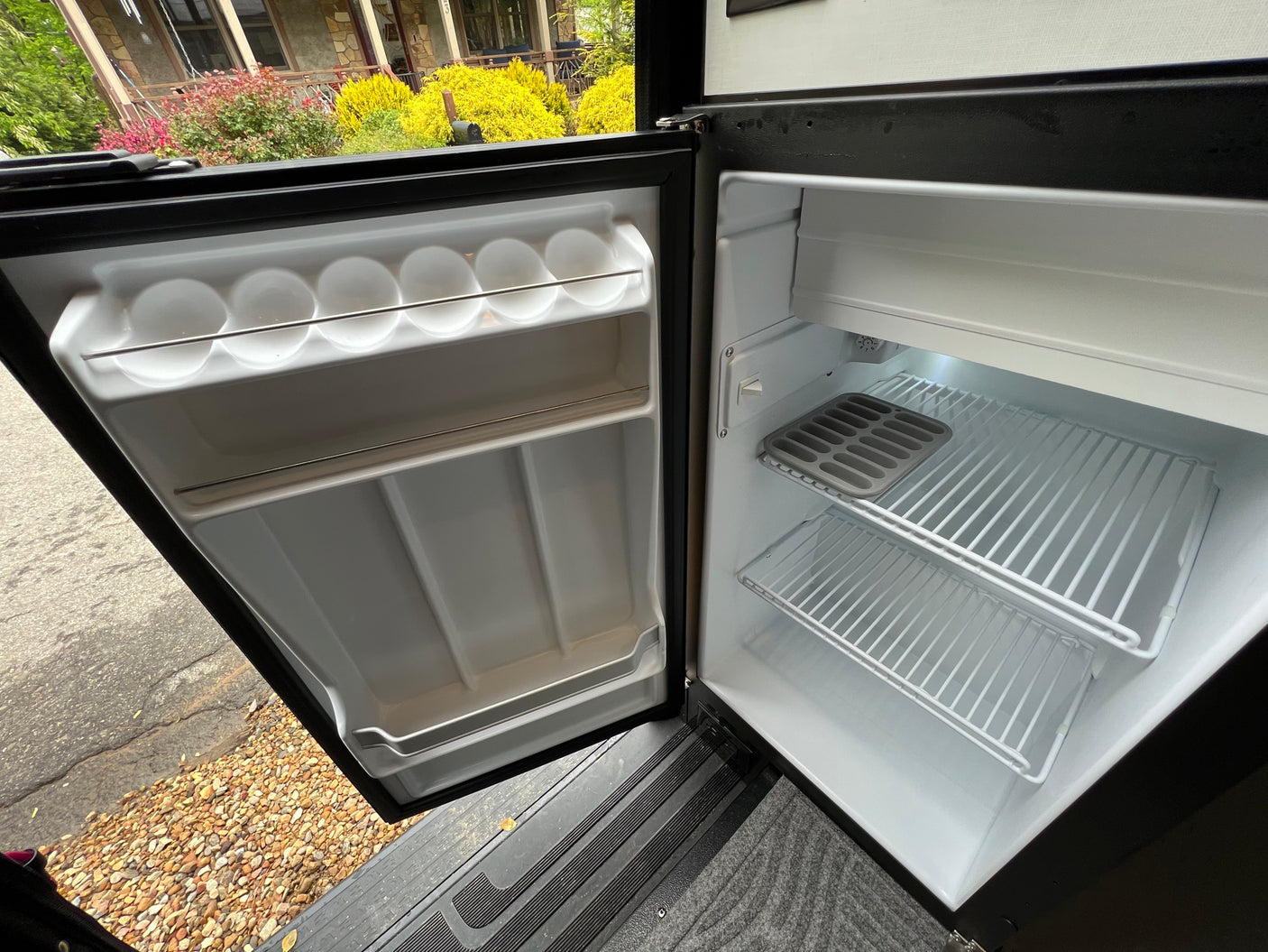Empty compact fridge in an RV rental, showing clean interior with shelves and an egg tray. Ideal for trips.