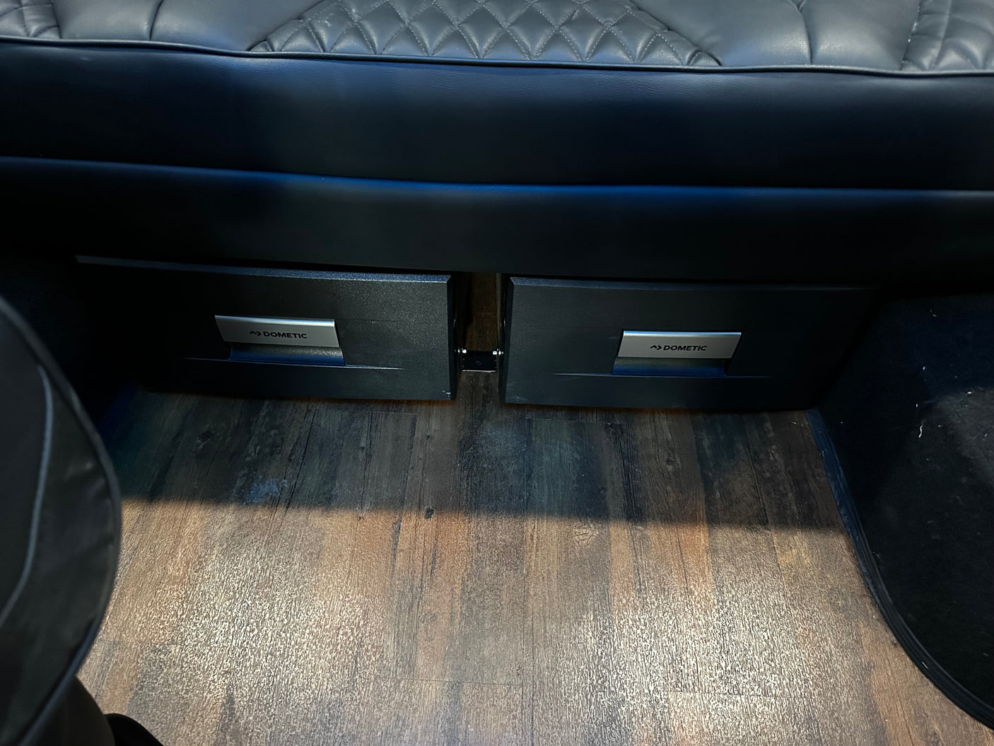 RV rental interior: Dometic under-seat drawer fridges, plush seating, and wood-look floor for comfortable campervan travel.