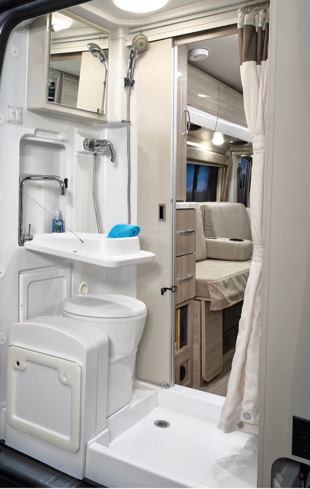 parked on a sunny street.|This RV rental interior features a comfortable grey bed — photo 6