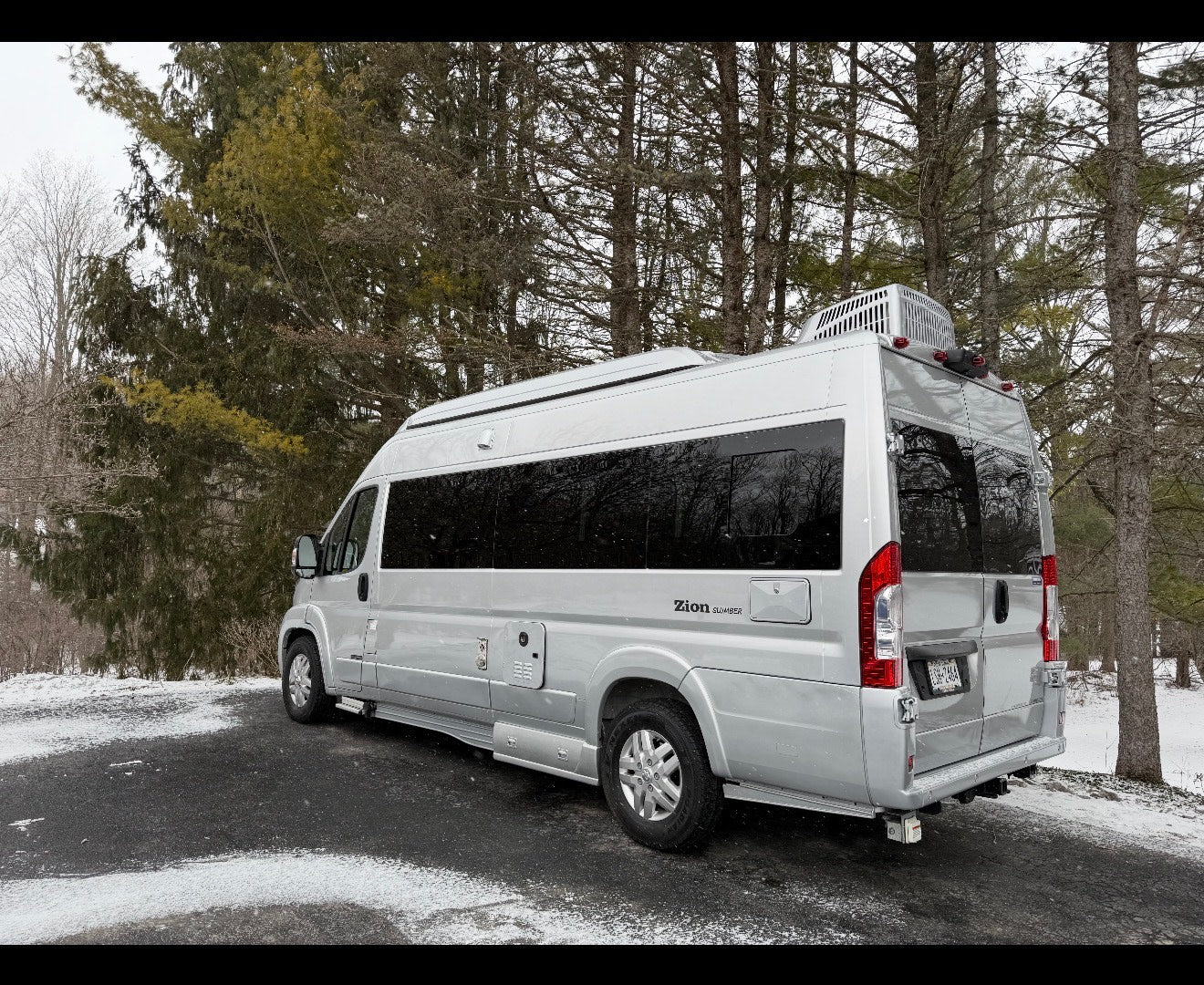 Silver Zion Slumber camper van RV rental parked in a snowy winter forest. Ideal for scenic road trips. — photo 4