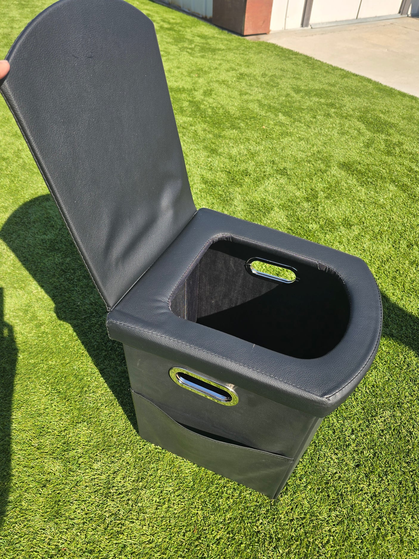 Compact black portable toilet with handles on artificial grass, great for your RV rental camping.