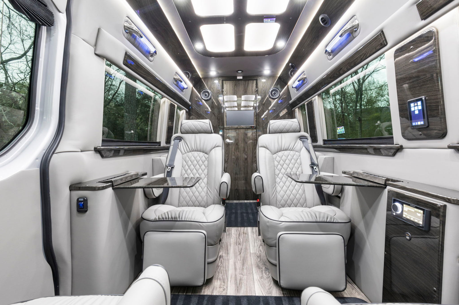 High-end RV rental interior: Two plush, facing seats, elegant wood trim, and ambient lighting create a luxurious and comfortable space.