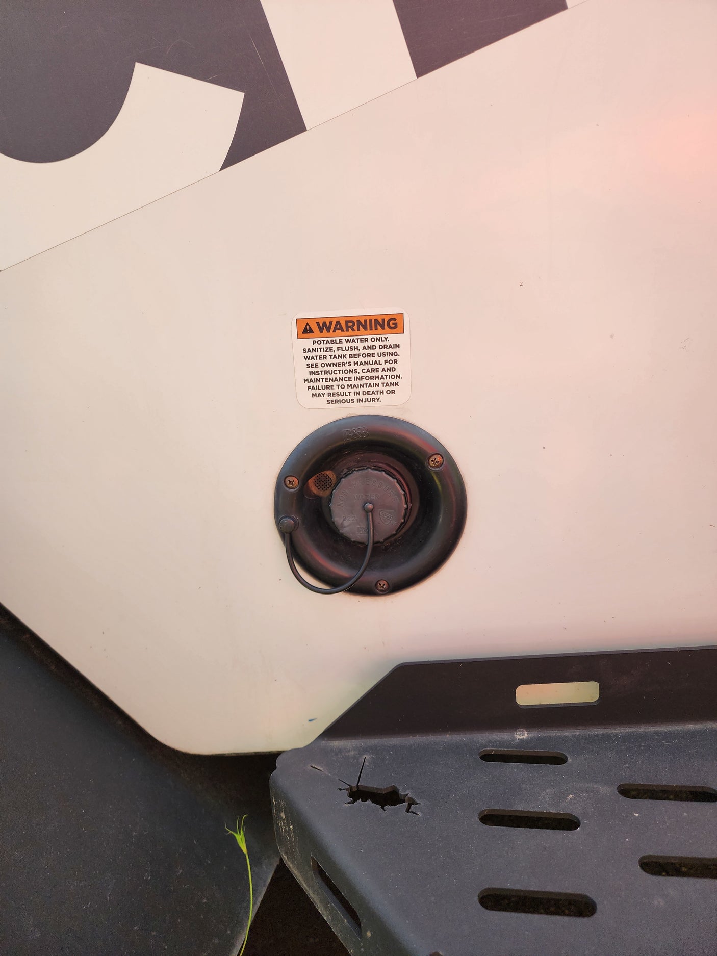 An RV rental's fresh water inlet with a warning about potable water and tank maintenance. Essential safety info.