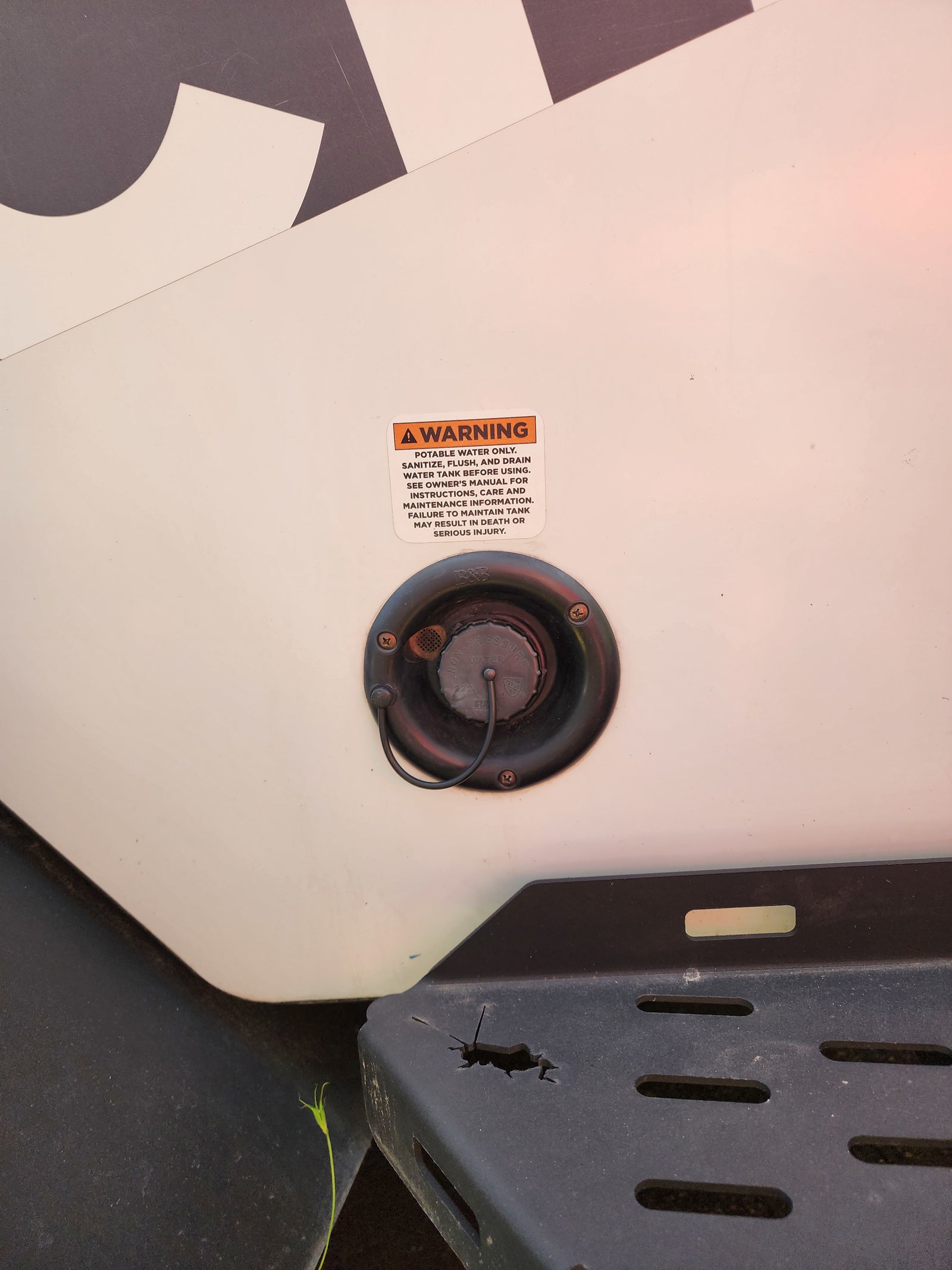 An RV rental's fresh water inlet with a warning about potable water and tank maintenance. Essential safety info.