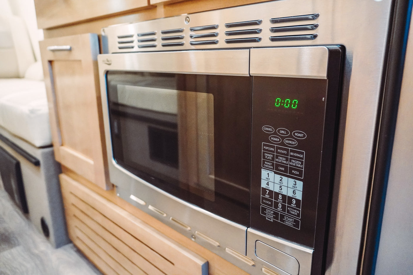 A stainless steel microwave oven, complete with its digital display and control panel, built into the kitchen of an RV rental.