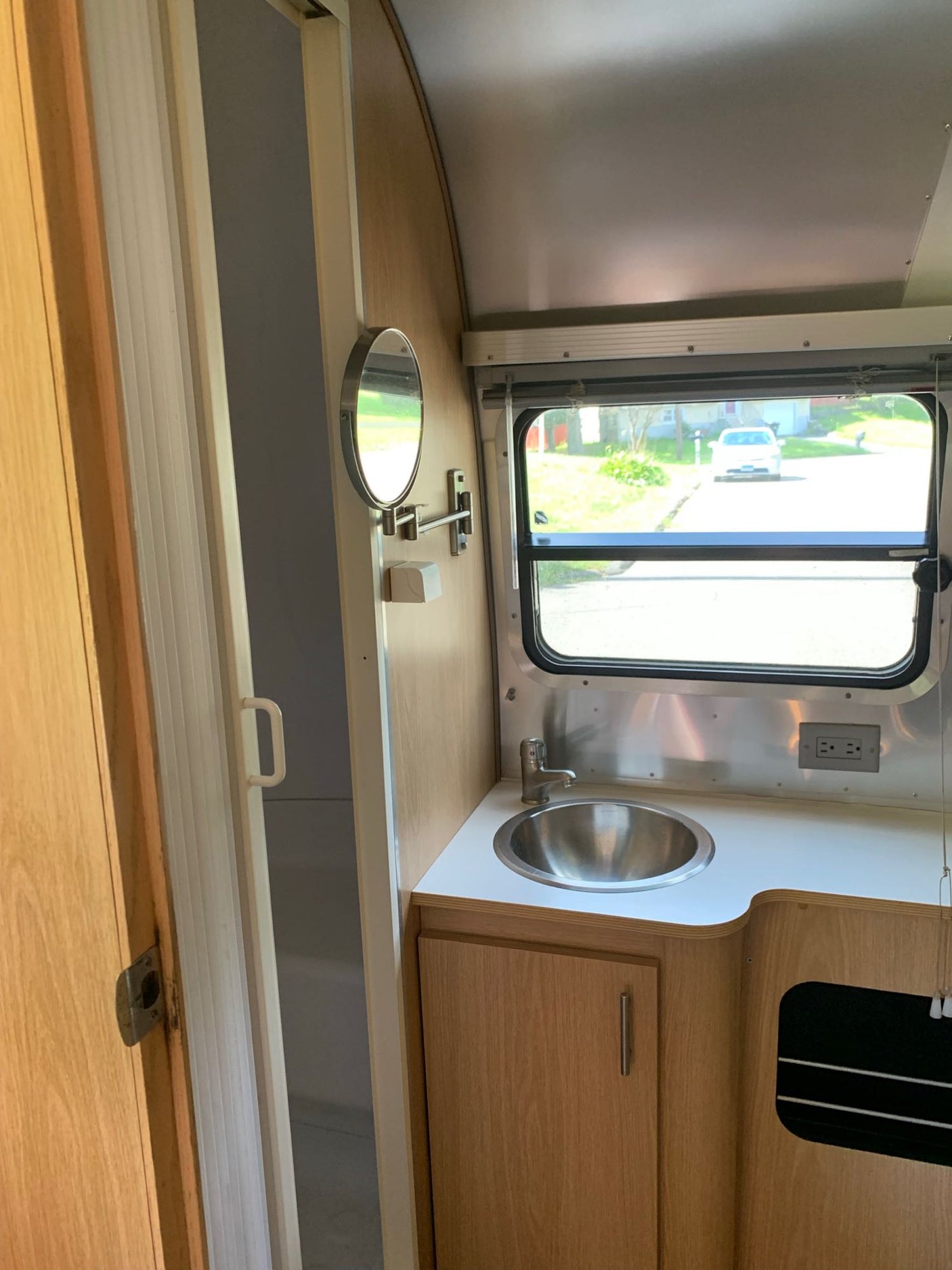 and glimpse of a bathroom are visible.|Compact RV rental interior featuring a cozy living area with grey cushions