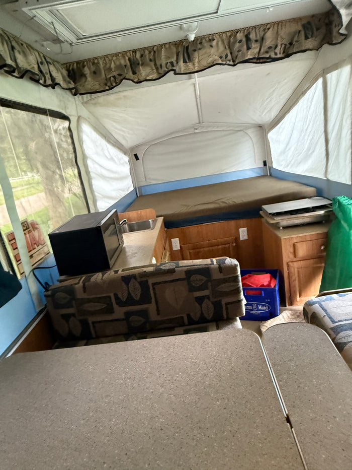 Experience a cozy RV rental pop-up camper interior with beds, kitchen, and dinette—perfect for your next camping trip.