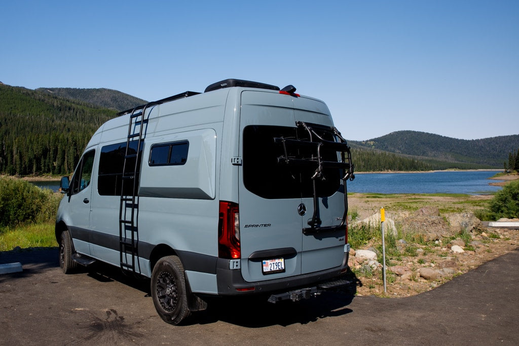 perfect for an RV rental adventure.|Stylish grey Mercedes Sprinter RV rental parked by a serene lake and forest — photo 6