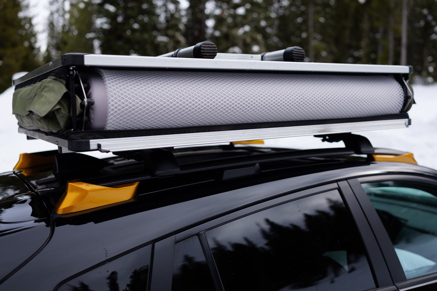 Packed rooftop tent on a black car's roof rack. A smart RV rental choice for agile snowy outdoor adventures.