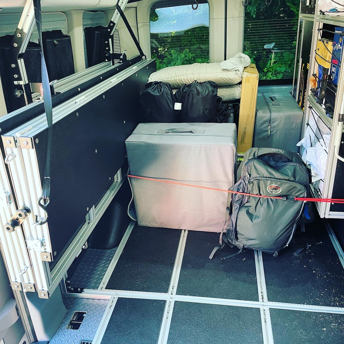 RV rental ready for adventure: Compact camper interior with modular storage, packed bags, and gear, showing efficient travel organization.