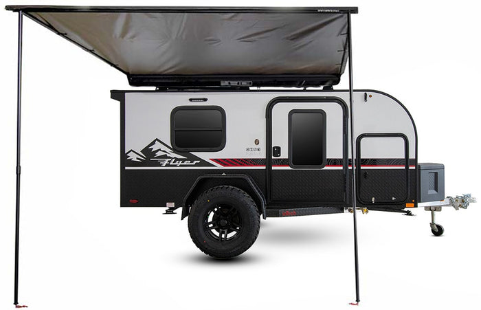 Explore the wild with this rugged black & grey Flyer Pursue off-road travel trailer, shown with an extended awning, ready for RV rental.