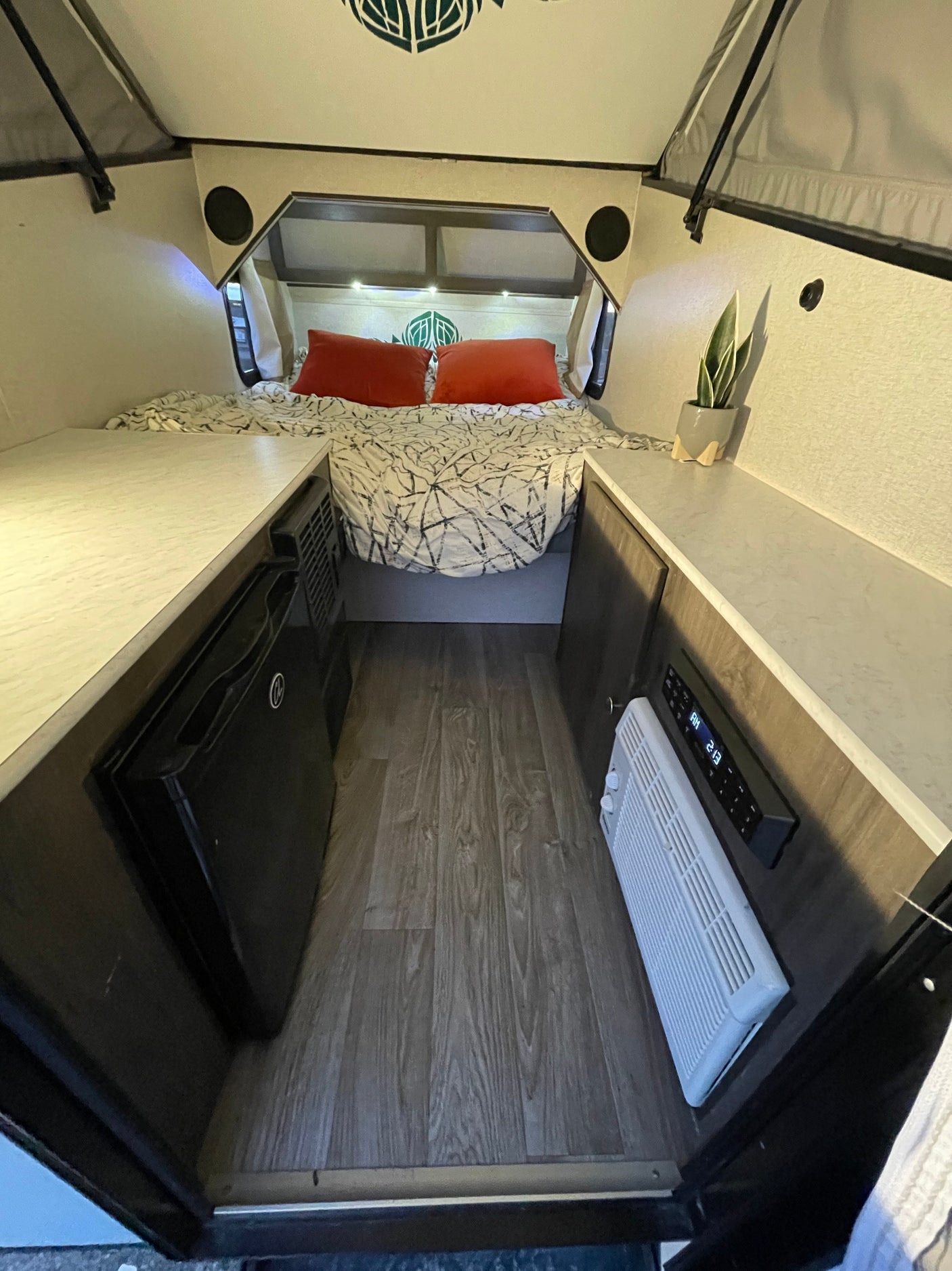 Cozy rv rental interior with bed, dual countertops, a mini-fridge, and climate control, offering a comfortable travel space.
