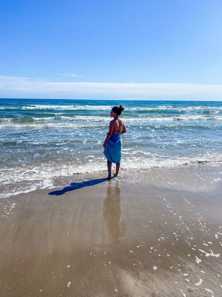 Person on beach, looking at serene ocean views. Find coastal bliss on your next RV rental trip.