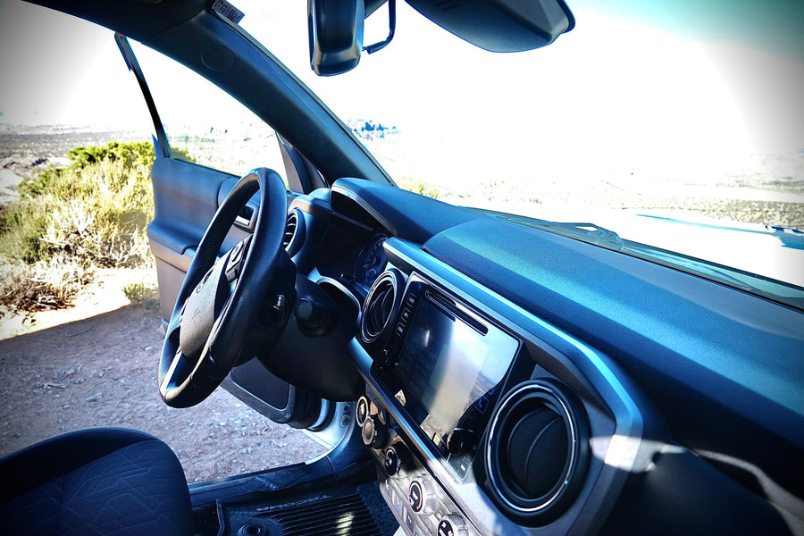 Interior view of a Toyota Tacoma truck with an open door to a vast dry landscape, ideal for travel or an rv rental.