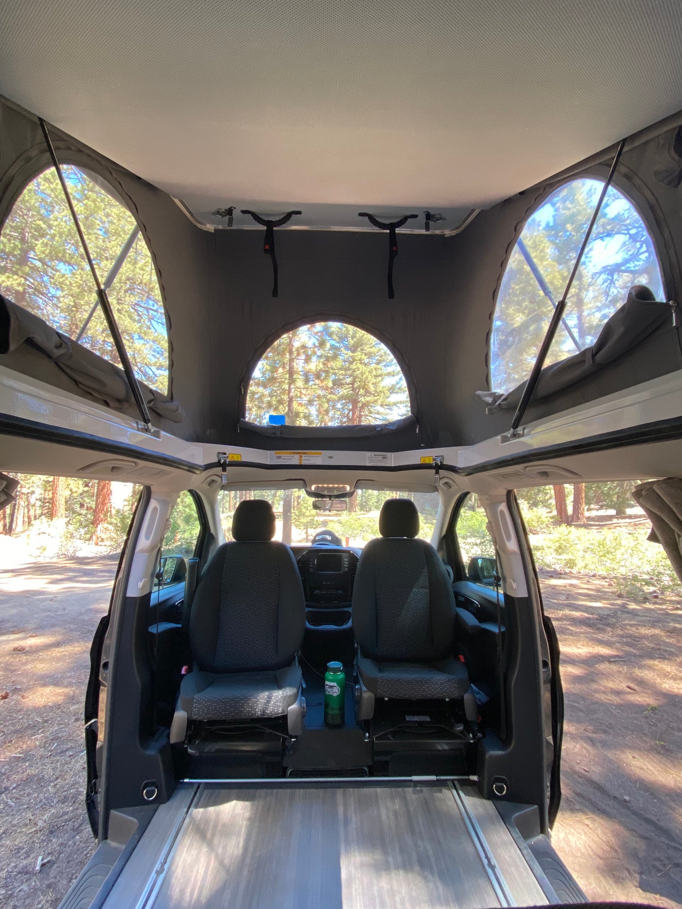 Experience the spacious interior of this rv rental, featuring a raised pop-top roof for panoramic views & comfortable front seating.