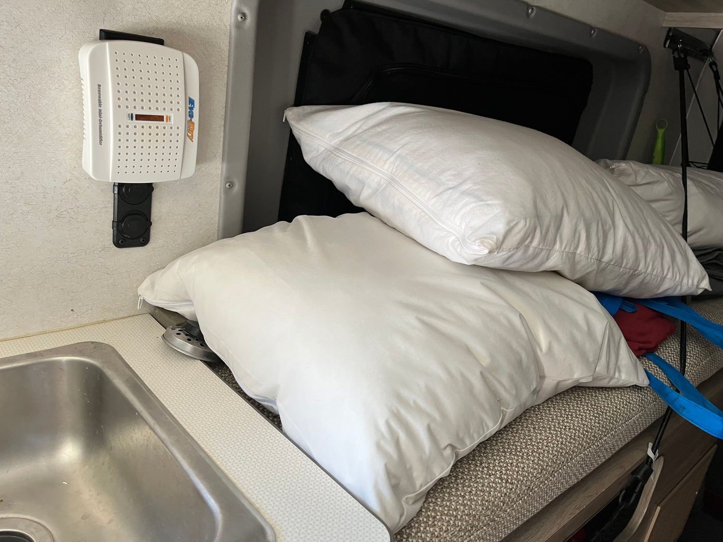 Inside an RV rental: Sink, pillows, and a wall-mounted dehumidifier for a comfortable and dry interior space.