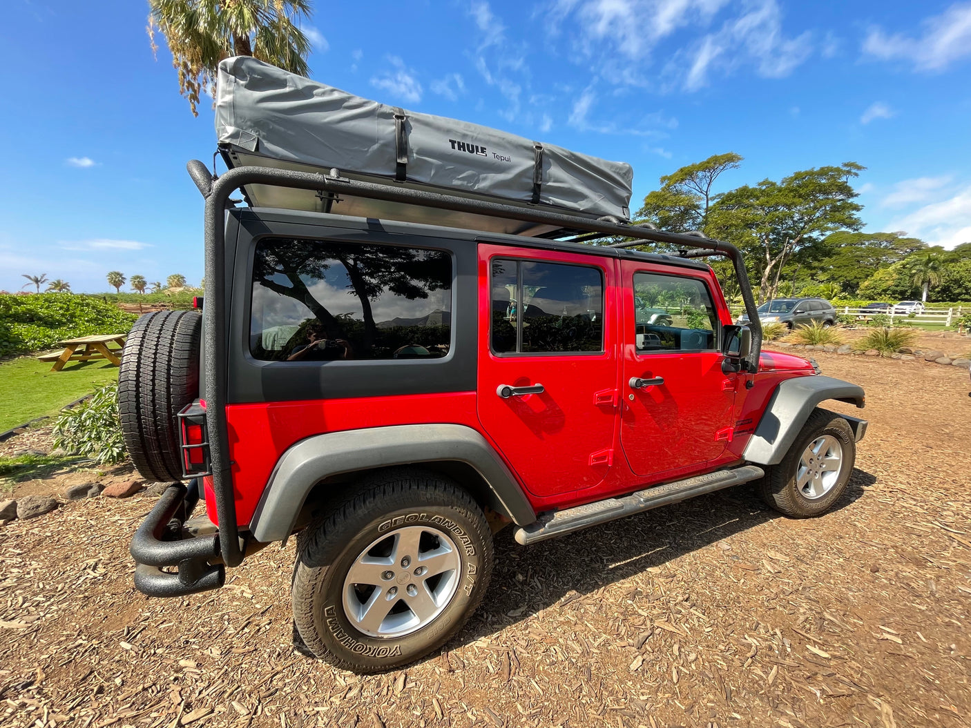 Bright red Jeep Wrangler with a Thule rooftop tent. Ideal for your next RV rental camping trip!