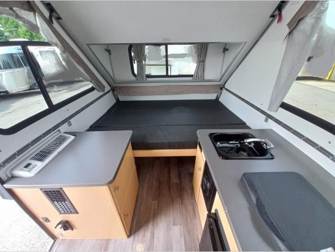 with a dog.|A light-colored A-liner pop-up camper rv rental with an external AC unit
