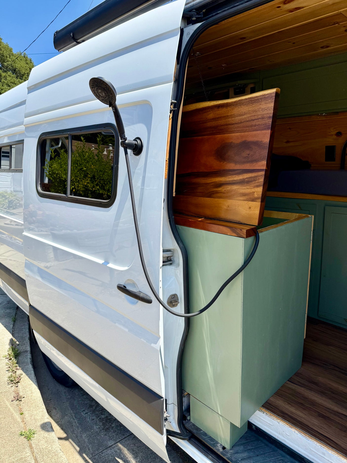 RV rental: Enjoy the outdoors with this camper van's convenient exterior shower and custom interior.
