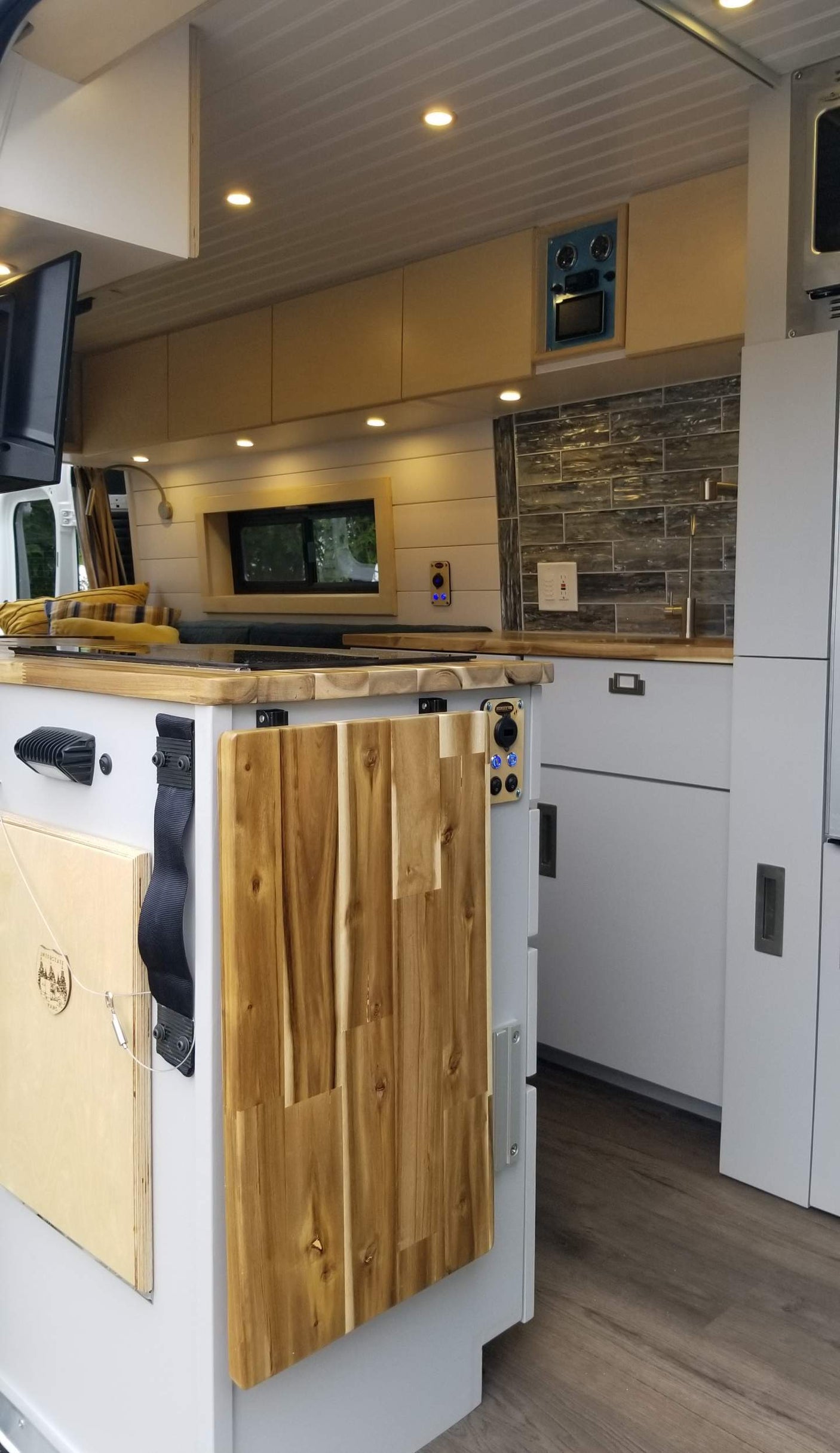 RV rental: modern kitchen with wood counters, light gray cabinets, tile backsplash, and ceiling spotlights.