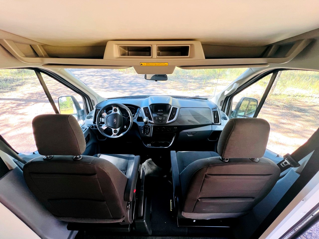 Inside an rv rental: View from rear of cabin showing driver's cockpit, seats, and road ahead. — photo 6