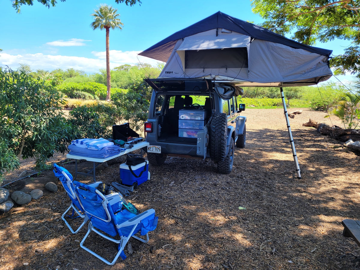 RV rental adventure setup: A Jeep with a rooftop tent and awning. Camp chairs, cooler, and stove are ready for outdoor car camping. — photo 5