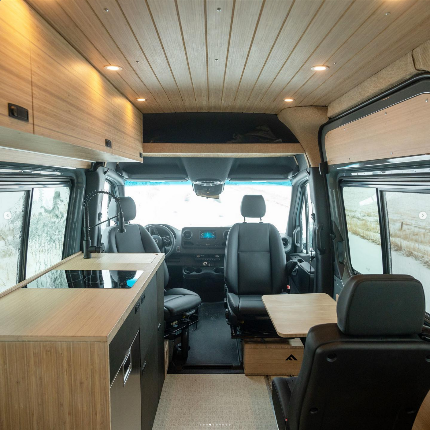 Inside a sleek **RV rental**! This modern camper van features wood ceilings, a kitchen, swivel seats, and warm lighting for comfortable **mobile living**.