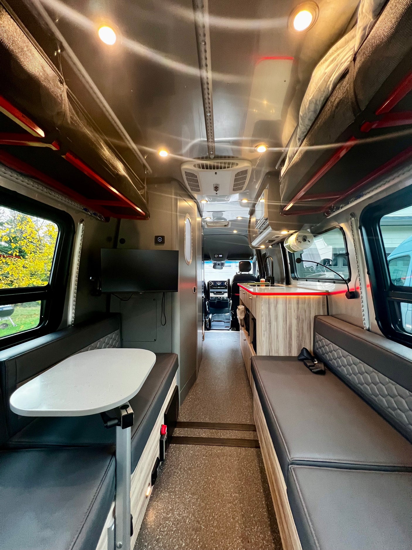 This RV rental features a well-equipped interior with a dinette, kitchen, and overhead bunk beds, leading to the cockpit.