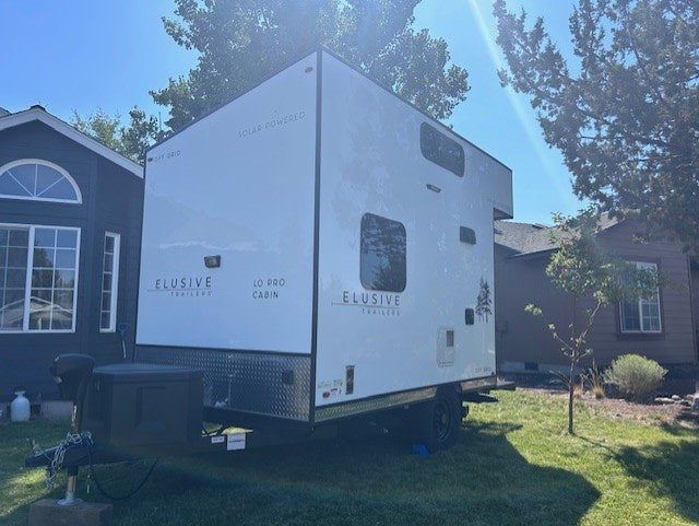 solar-powered "Elusive Trailers" off-grid camper is an ideal rv rental for a rugged outdoor adventure.|Modern white Elusive Trailers LO PRO CABIN