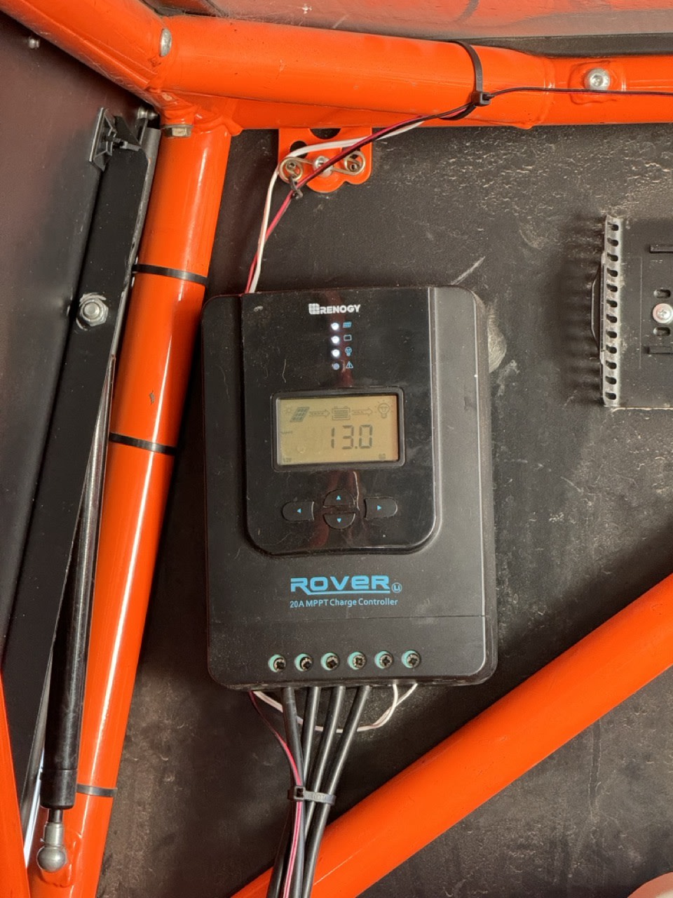An RV rental's Renogy Rover solar charge controller, displaying 13.0V, vital for off-grid battery power.