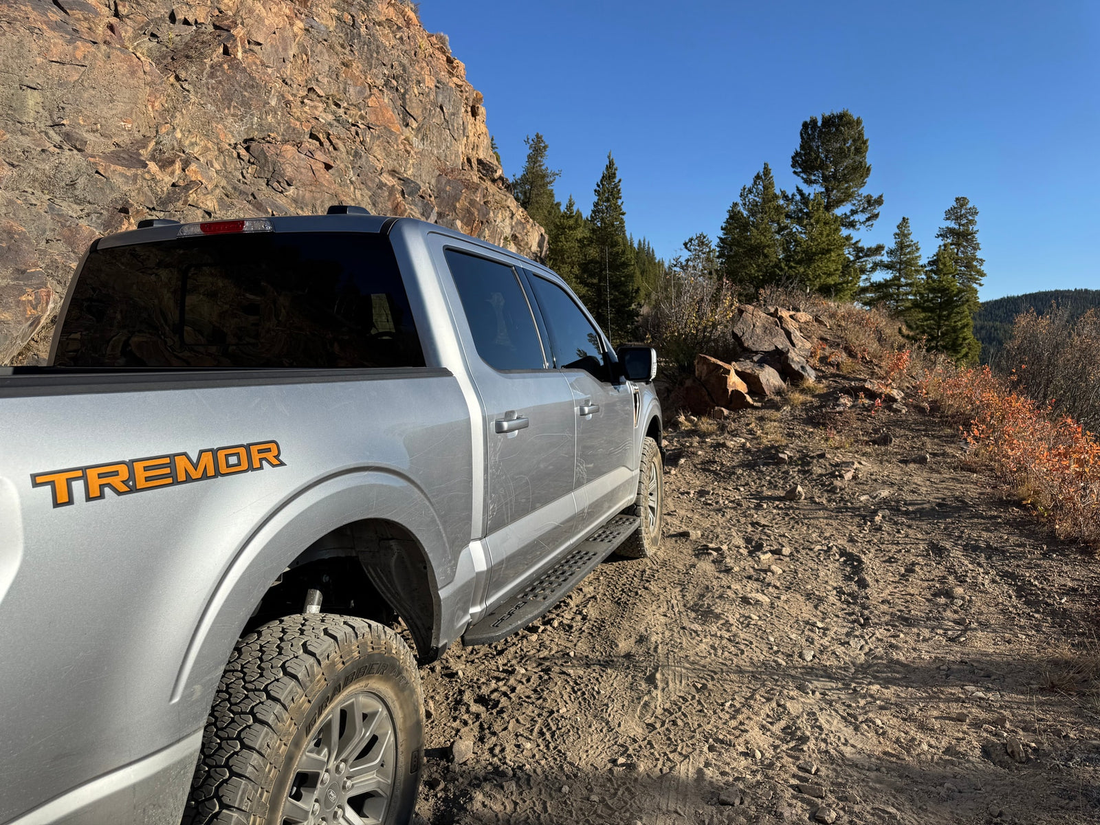 A silver Ford F-150 Tremor truck on a dirt mountain trail. Ideal for rugged off-road trips beyond typical RV rental roads.