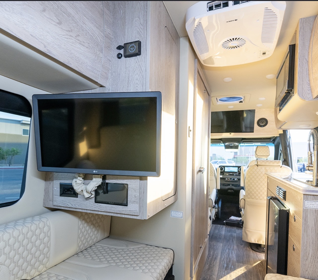 Explore this RV rental's cozy interior, featuring a flat-screen TV, comfortable seating, and a kitchenette, leading to the cockpit.